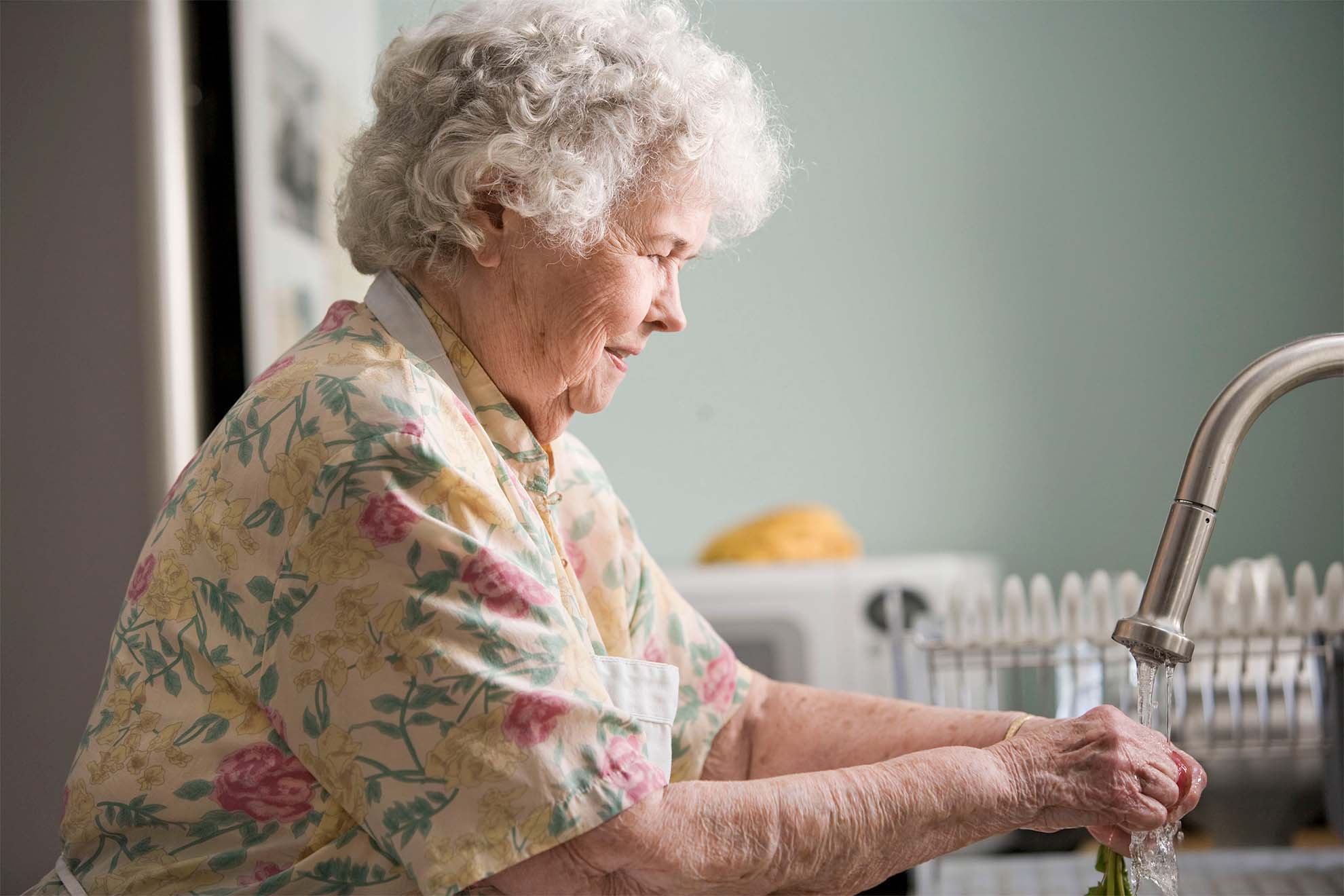 elderly lady washing dishes in the sink