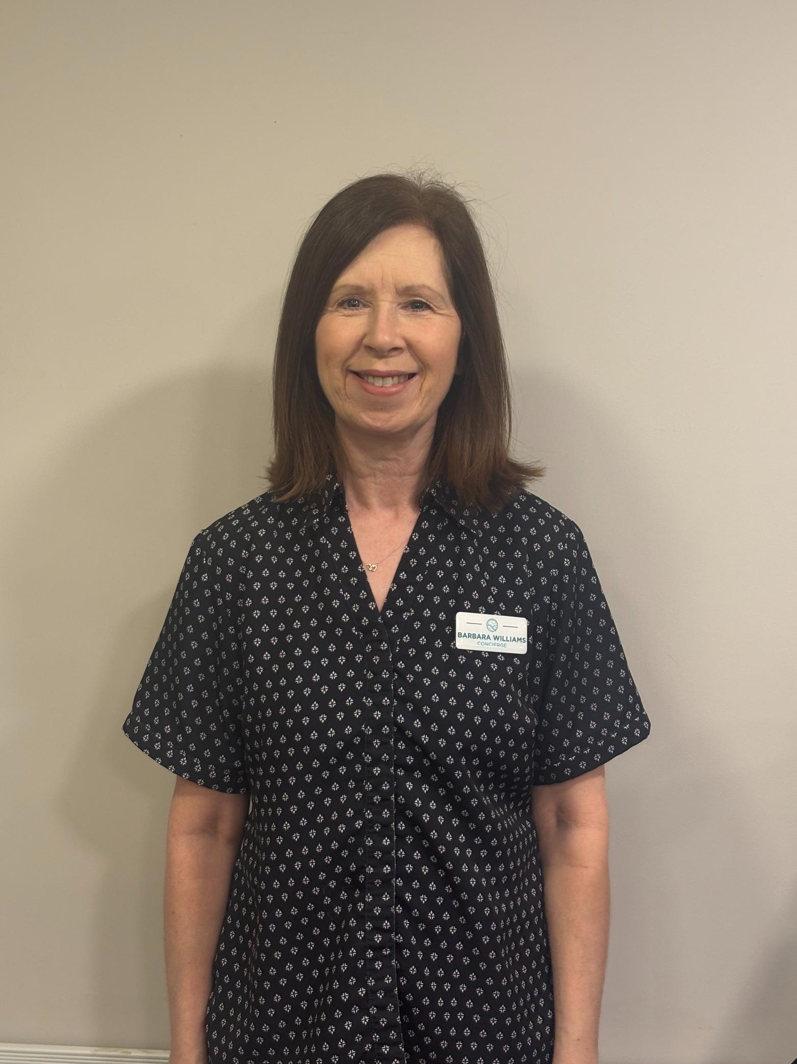 woman with brown hair wearing a blue and white patterned blouse having her photo taken for the team page