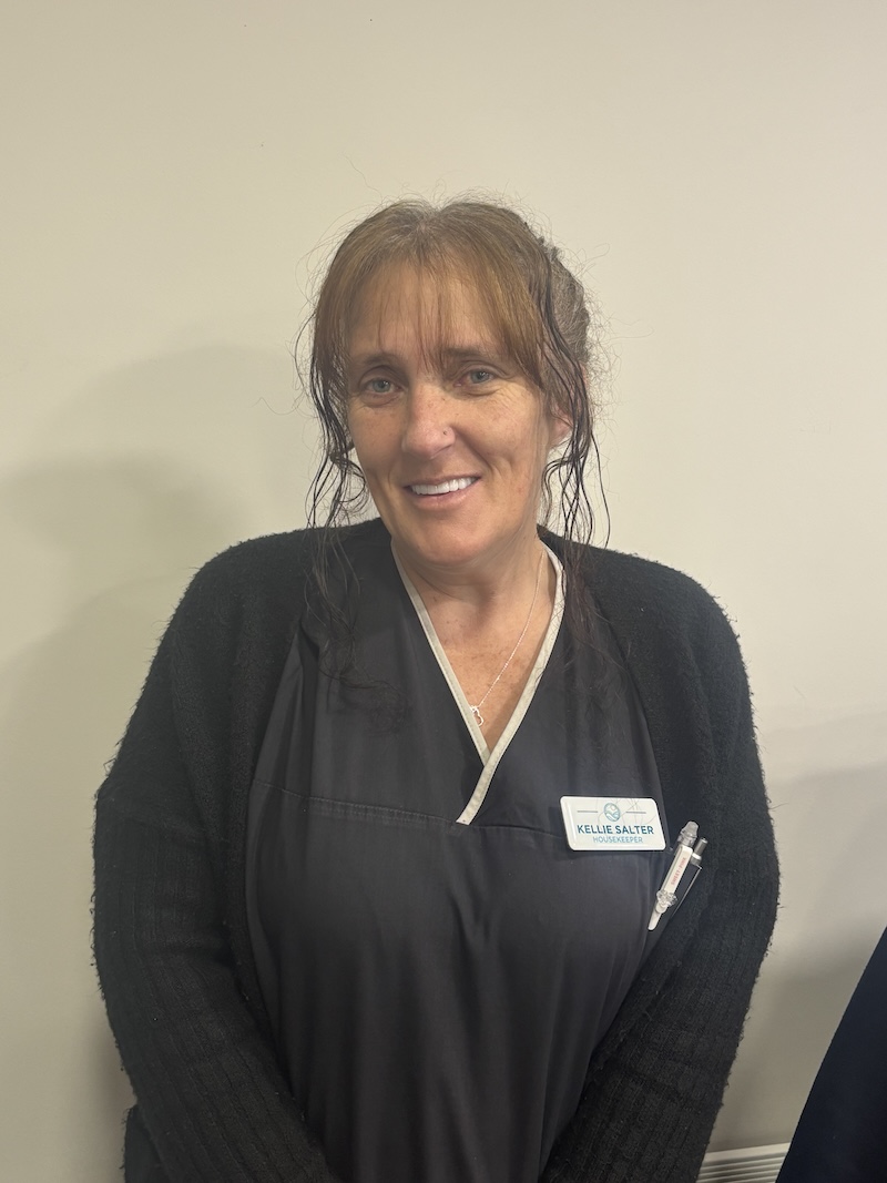 woman with brown hair wearing a black housekeeper uniform having her photo taken for the team page