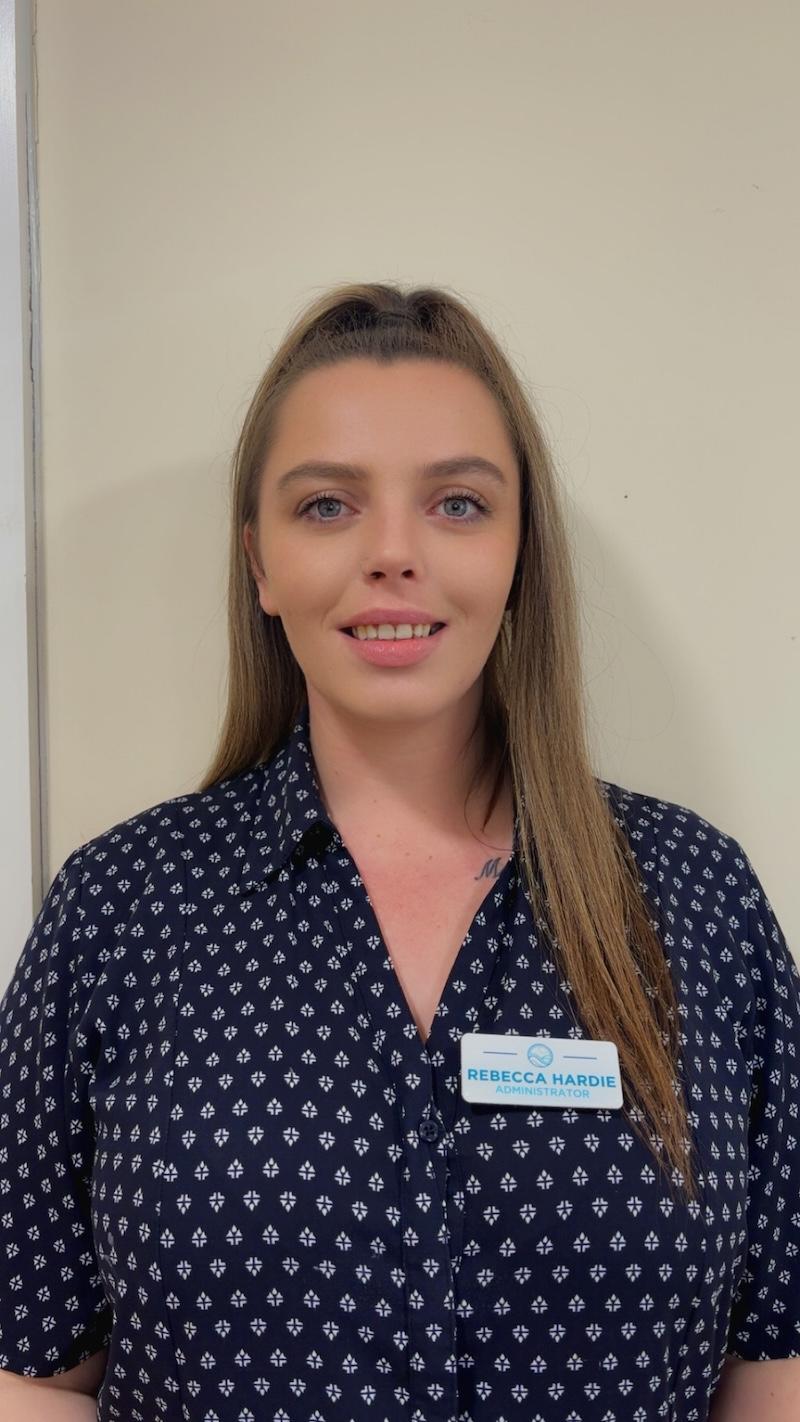 woman with brown hair wearing a blue and white patterned blouse having her photo taken for the team page