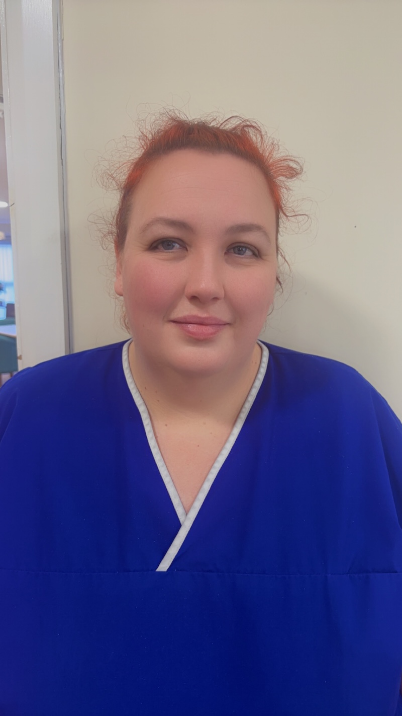 female unit lead wearing a dark blue uniform smiling having her headshot taken for the website