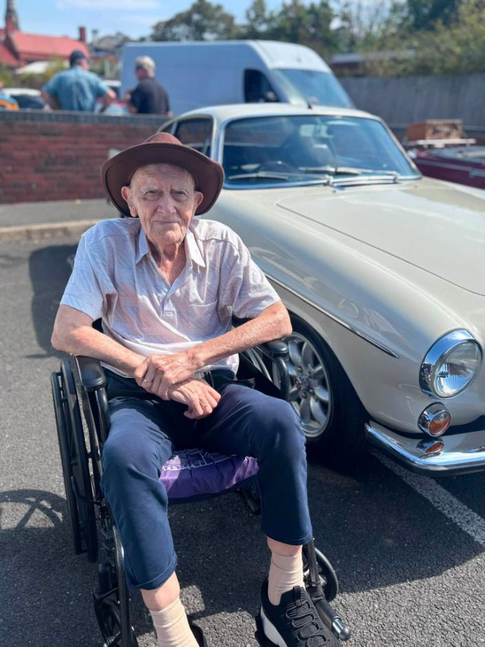 older man in wheelchair by car