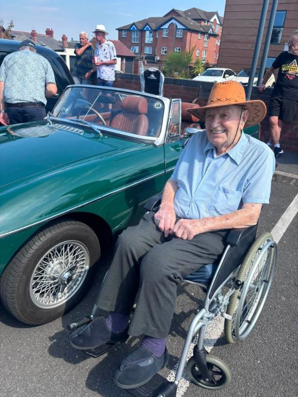 older man in wheelchair by car