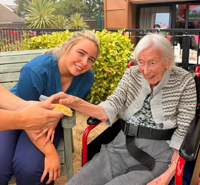 resident sat with a carer touching a lizard for pet therapy