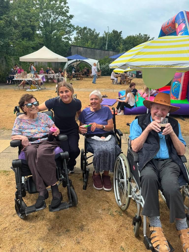 residents in wheelchairs smiling by a bounce house